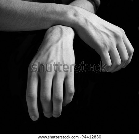 Black and white study of human hands against a black background.