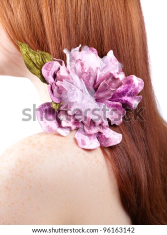 Detail on the hair of a red head woman wearing a nice flower.