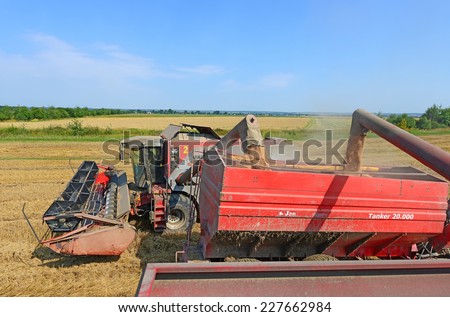 Kalush, Ukraine - AUGUST 10: Overloading grain harvester into the grain tank of the tractor trailer. in the field near the town Kalush, Western Ukraine August 10, 2014