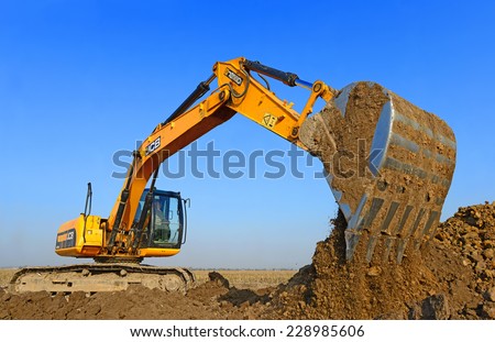 Kalush, Ukraine  October 14: Modern JCB excavator on the highway pipeline performs excavation work in the field near the town Kalush, Western Ukraine October 14, 2014