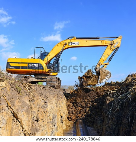 Kalush, Ukraine October 7: Modern JCB excavator on the highway pipeline performs excavation work in the field near the town Kalush, Western Ukraine October 7, 2014