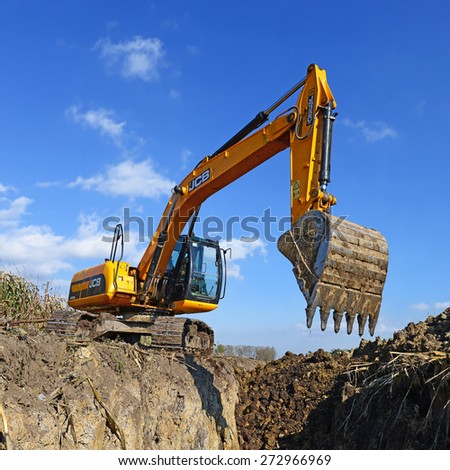 Kalush, Ukraine - October 7: Modern JCB excavator on the highway pipeline performs excavation work on the field near the town Kalush, Western Ukraine on October 7, 2014