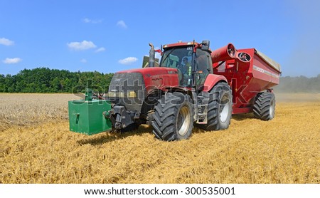 Kalush, Ukraine - AUGUST 11: Modern  tractor with a tank for transportation  grain in the field near the town Kalush, Western Ukraine August 11, 2014.