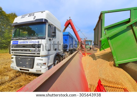 Kalush, Ukraine - August 12: Overloading the grain silo tractor trailer in the car using auger tractor-drawn auger loader in the field near the town Kalush, Western Ukraine August 12, 2015