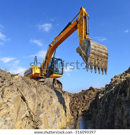 Kalush, Ukraine   October 7: Modern JCB excavator on the highway pipeline performs excavation work in the field near the town Kalush, Western Ukraine October 7, 2014