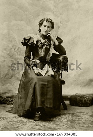 USA - MASSACHUSETTS - CIRCA 1897 - A vintage photo of a young woman. The woman is sitting in a chair. She is dressed in a beautiful Victorian style dress. A photo from the Victorian era. CIRCA 1897