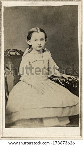 USA - CONNECTICUT - CIRCA 1863 A vintage Cartes de visite photo of a young girl sitting in a chair and wearing a dress with pig tails in her hair. A photo from the Civil War Victorian era. CIRCA 1863