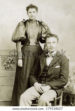 USA - VERMONT - CIRCA 1895 A vintage cabinet card photo of a young couple. She is standing and he is sitting. They are wearing Victorian style clothing. Photo is from the Victorian era. CIRCA 1895