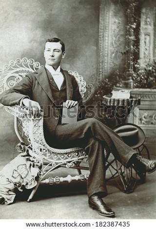 USA - COLORADO - CIRCA 1895 A vintage cabinet card photo of a gentleman holding a fedora hat. He is sitting in a chair while holding a book. Photo from the Victorian era. CIRCA 1895