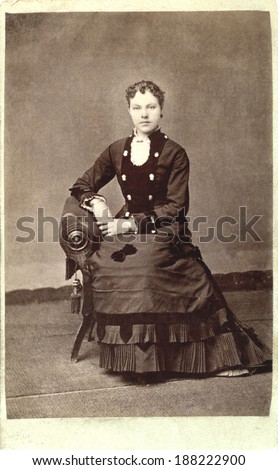 USA - ILLINOIS - CIRCA 1880 A vintage carte de visite photo of a young lady dressed in a Victorian bustle style dress. She is sitting in a chair. Photo is from the Victorian era. CIRCA 1880