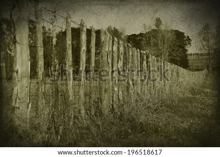 A row of wooden pickets making a fence. The photo is black and white and has texture applied to make it look old,vintage and worn.