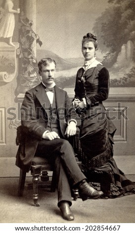 USA - MINNESOTA - CIRCA 1880 Vintage Carte de Viste photo of young couple. The gentleman is sitting and the lady is standing dressed in a Victorian style dress. Photo from Victorian era. CIRCA 1880