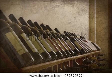 A grunge textured photo of several bottles of wine on a wine rack. Perfect display of different varieties.