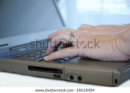 Closeup of hand entering information on laptop computer.