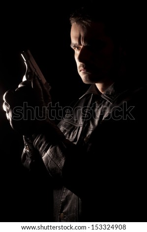 Handsome young man in leather jacket holding a gun
