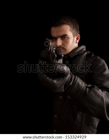 Handsome young man in leather jacket holding a gun