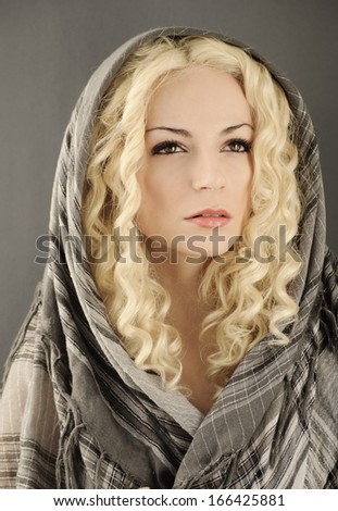 Beautiful young woman with curly blond hair with head wrapped with grey scarf