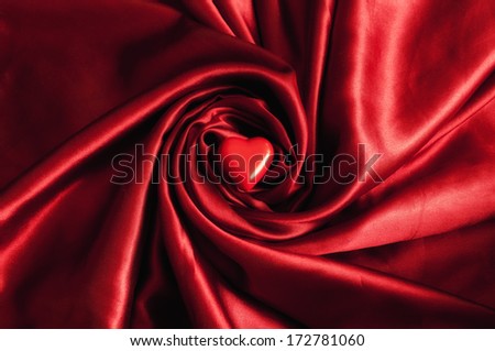 Red heart on a beautiful red satin sheet