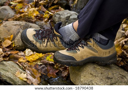 View of two feet wearing hiking shoes with autumn leaves in background