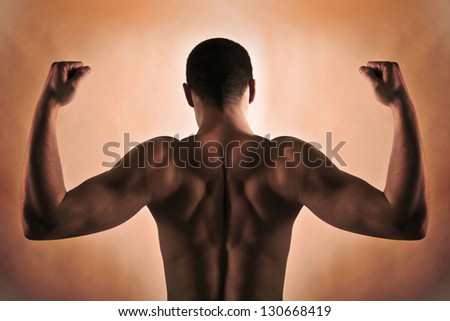 fitness model posing with perfect muscular back on red background no clothes on