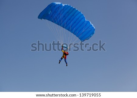 man on clear blue sky with parachute from behind