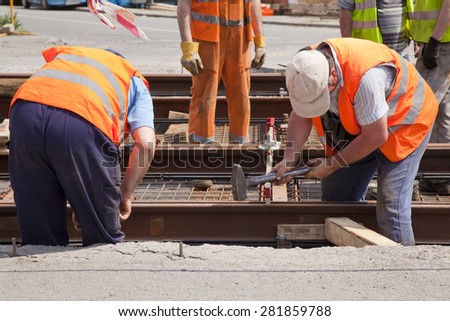 railway worker team in the street with a swinging a hammer