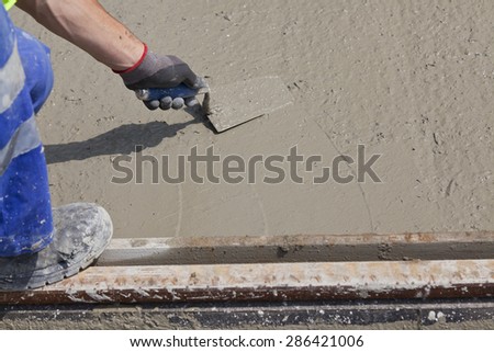 worker hand working with wet cement in boots