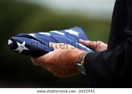 Man\'s hands holding a folded American flag