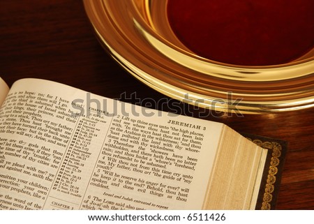 Close up of about half a page of a pulpit Bible next to a church collection plate. About half of the brass plate is visible.