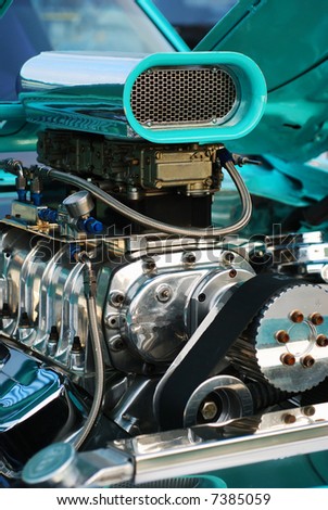 Vertical close-up of a hotrod engine showing the air intake, valve covers, drive belts, etc.