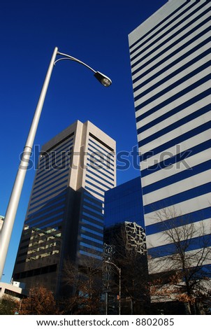 Two modern office buildings with a modern street light appearing to arch over one of them.