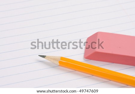 Pencil and eraser laying on blank lined paper. Concept of education.