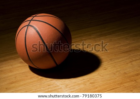 Basket ball sitting on basket court in the spotlight.