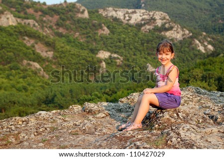 happy little girl sitting on mountain top