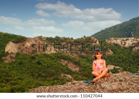 beautiful little girl sitting on mountain top