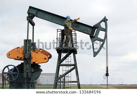 oil worker stands at the pump jack