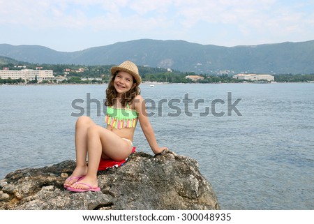 little girl sitting on a rock by the sea summer vacation