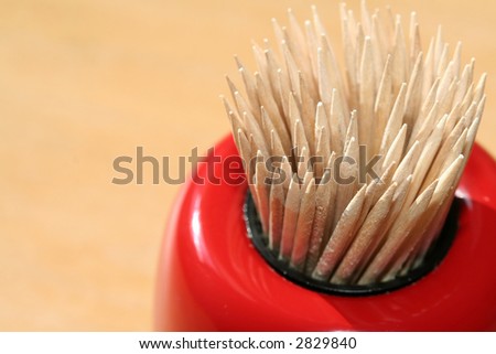 Toothpicks in a red lacquer ware holder.