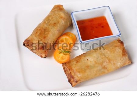 A pair of egg rolls with dipping sauce.