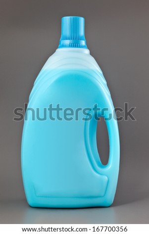 Transparent detergent plastic bottle with blue liquid isolated on gray.