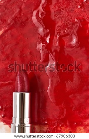 Red lipstick with gloss on the background of smeared red lipstick.