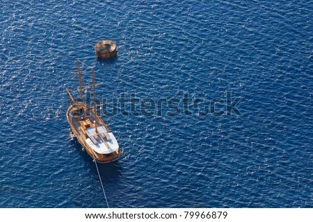 Vintage wooden sailing boat sailing towards the island of Santorini. Sea background.
