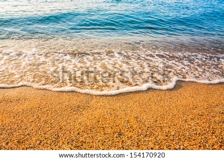Soft sea ocean waves wash over golden sand background