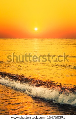 Soft sea ocean waves wash over golden sand background. Sunset, sunrise, sun