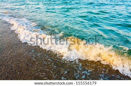 Soft sea ocean waves wash over sand background. Sunset, sunrise