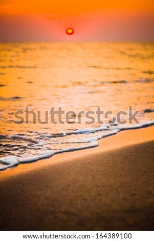 Soft sea ocean waves wash over golden sand background. Sunset, sunrise, sun. Close focus waves