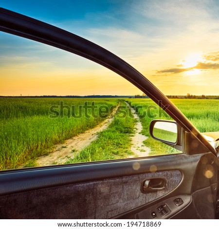 Dirty rural road in field, meadow, countryside. View from car window. Freedom and dream concept