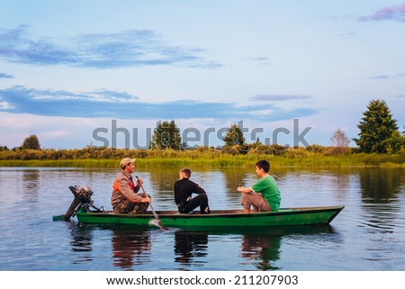 MINSK, BELARUS - JULY 25: Belarusian Man And Two Boys Sailing In Old Boat On River At Sunset Of Summer Day On July 25, 2013 in Minsk, Belarus