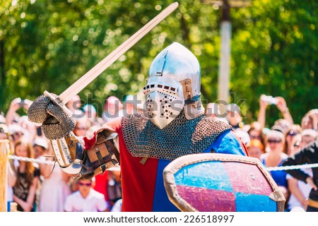 Historical Restoration Of Knightly Fights. Summer Time. Knight In A Fight With Sword