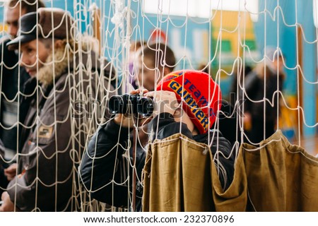 GOMEL, BELARUS - JANUARY 1, 2011: Unrecognizable Belarusian secondary school pupil boy watching with binoculars for school competitions \